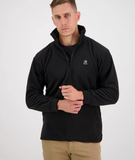 A man wearing a black swanndri motu quarter-zip fleece pullover with a small swanndri logo on the left chest, paired with khaki pants, photographed against a light gray studio background.